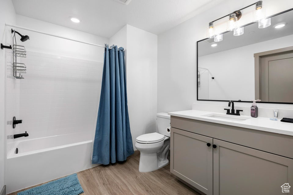 Full bath featuring wood finished floors, shower / bath combo, vanity, and recessed lighting