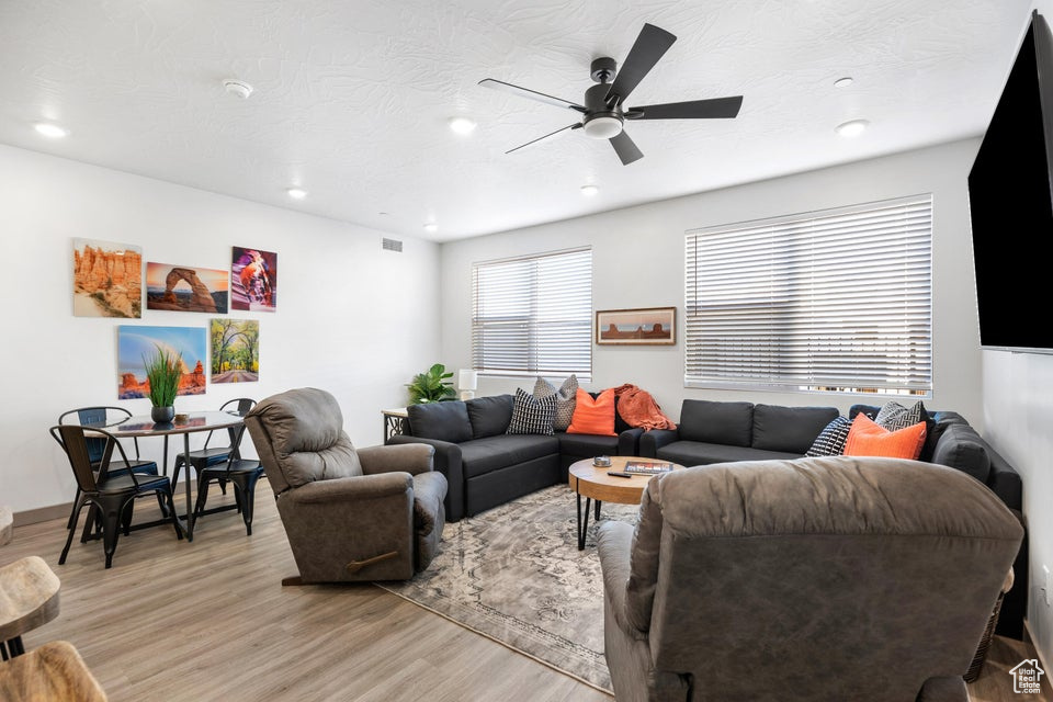Living room with light wood-type flooring, recessed lighting, and a ceiling fan