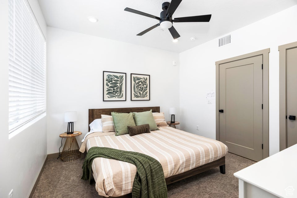 Carpeted bedroom featuring ceiling fan and baseboards