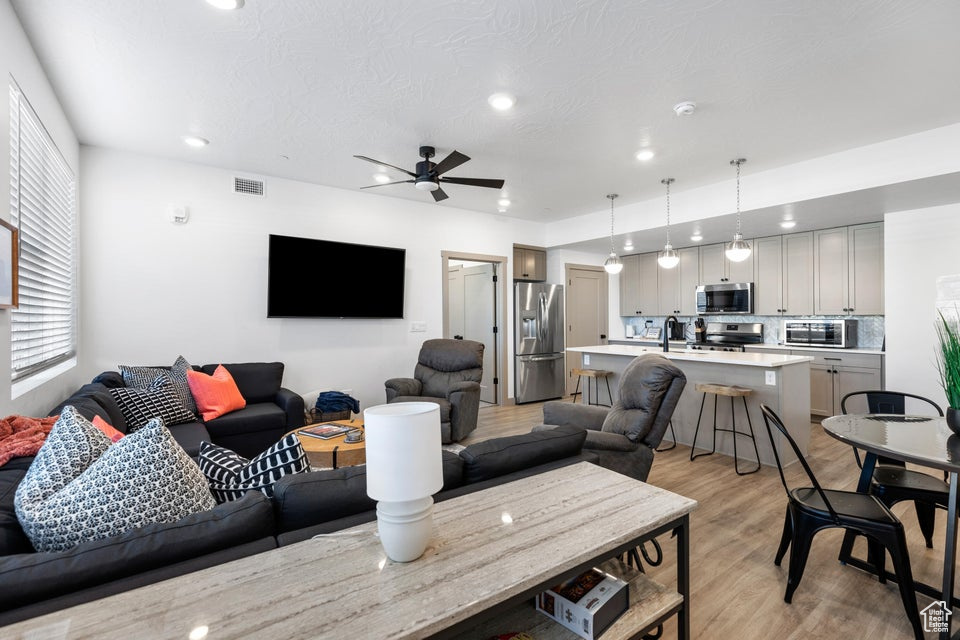Living area featuring light wood-style floors, a ceiling fan, and recessed lighting