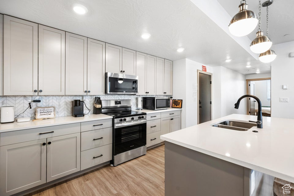 Kitchen featuring appliances with stainless steel finishes, light wood-type flooring, tasteful backsplash, light countertops, and recessed lighting