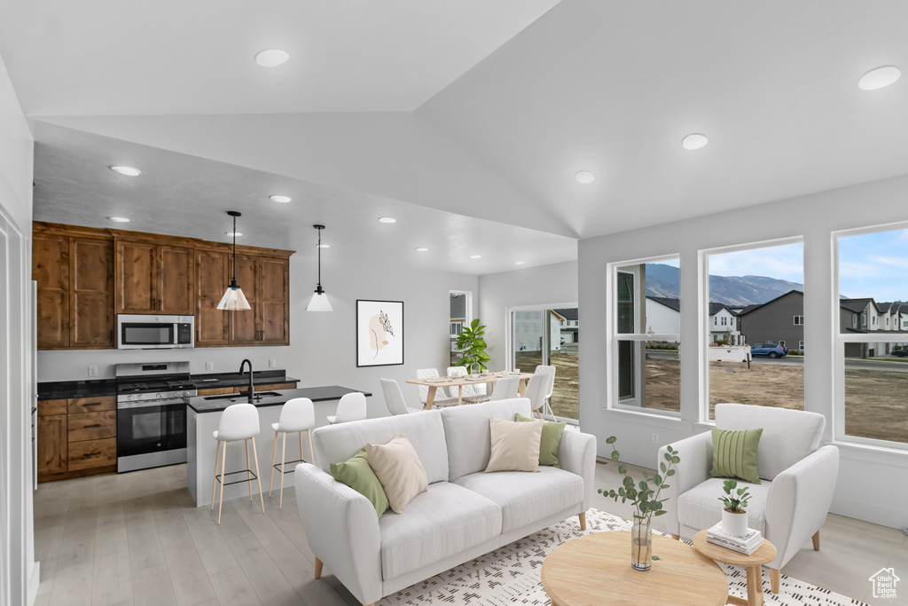 Living area featuring lofted ceiling, recessed lighting, and light wood-style floors