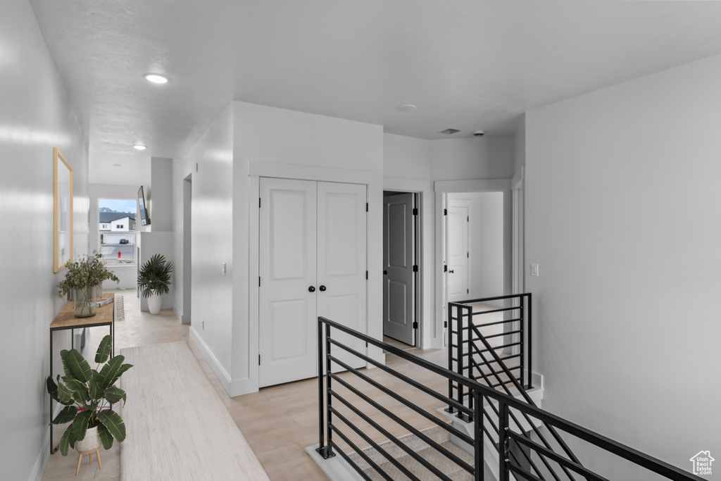 Hall featuring an upstairs landing, light wood finished floors, and recessed lighting