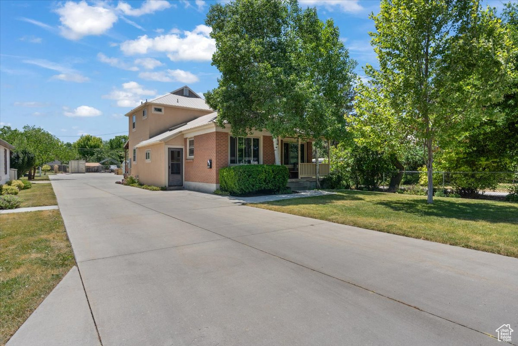 Obstructed view of property featuring brick siding, driveway, a front lawn, and a porch