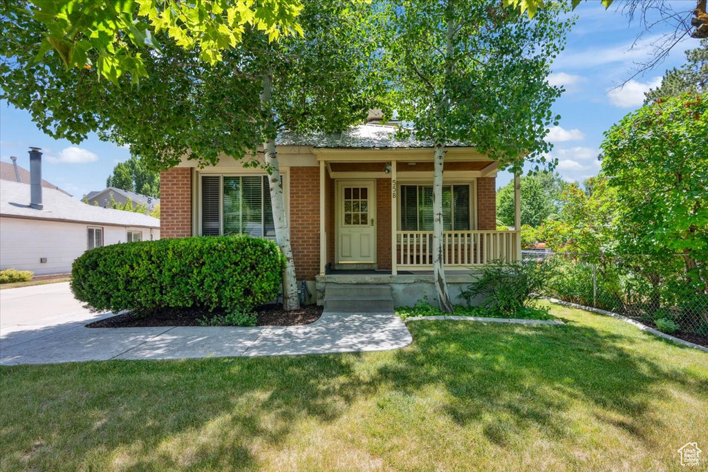 View of front of home with brick siding, a porch, and a front yard