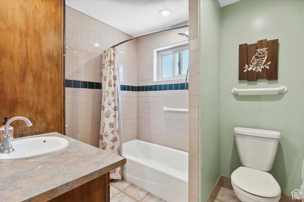 Bathroom featuring tile patterned floors, shower / bath combo with shower curtain, and vanity