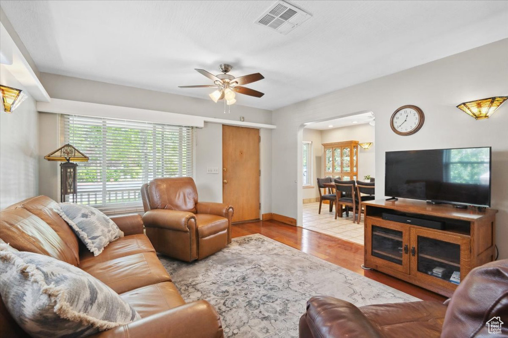 Living room with healthy amount of natural light, ceiling fan, wood finished floors, and arched walkways