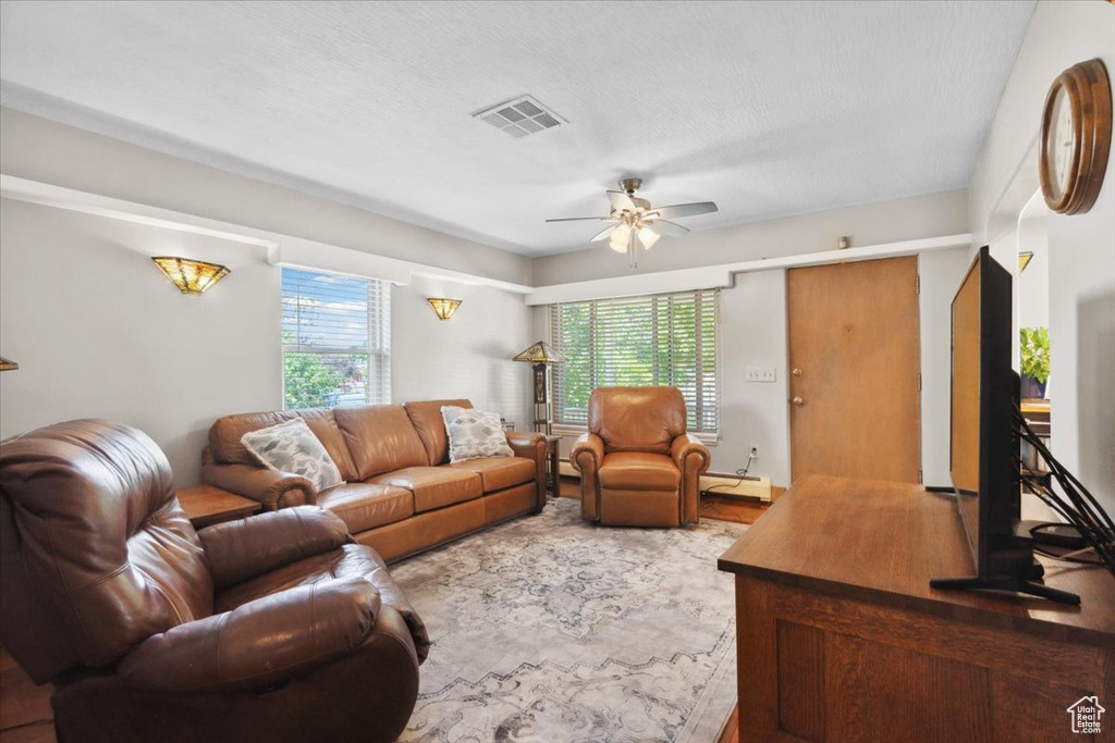 Living area featuring ceiling fan, a baseboard heating unit, and wood finished floors