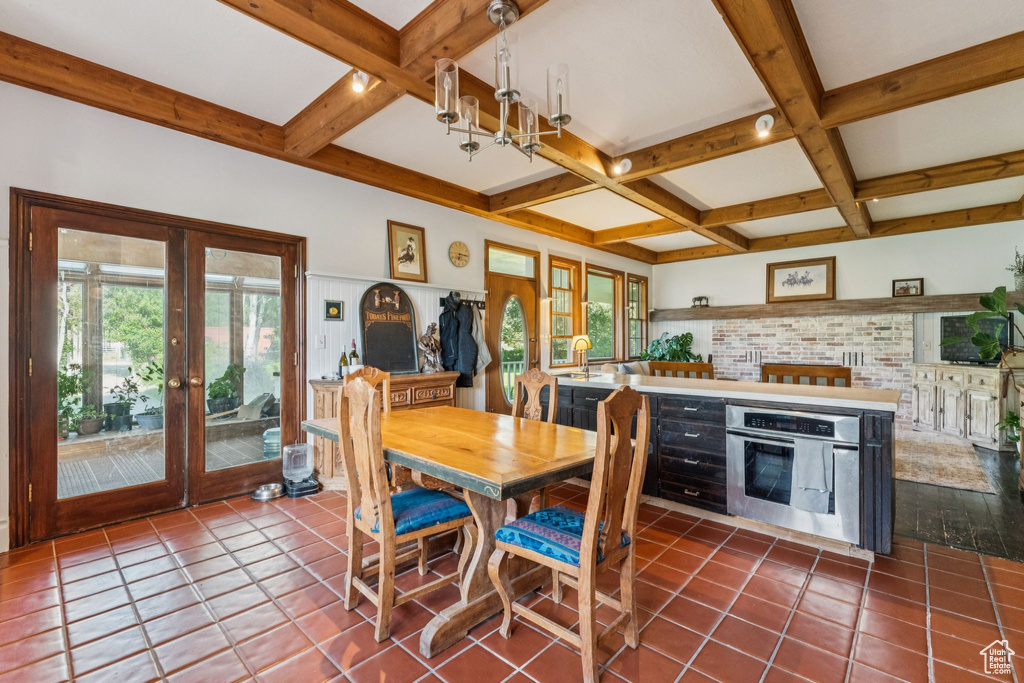 Dining space featuring coffered ceiling, beam ceiling, french doors, dark tile patterned flooring, and a chandelier