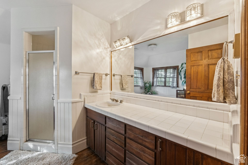 Full bathroom featuring vanity, wood finished floors, a shower stall, and a wainscoted wall