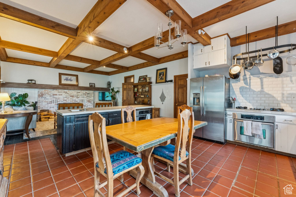 Dining room featuring beamed ceiling, dark tile patterned floors, and coffered ceiling
