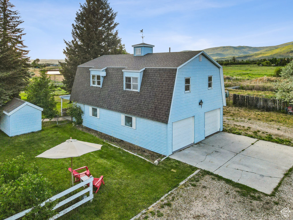 Rear view of house with a shingled roof, a gambrel roof, a garage, driveway, and a mountain view
