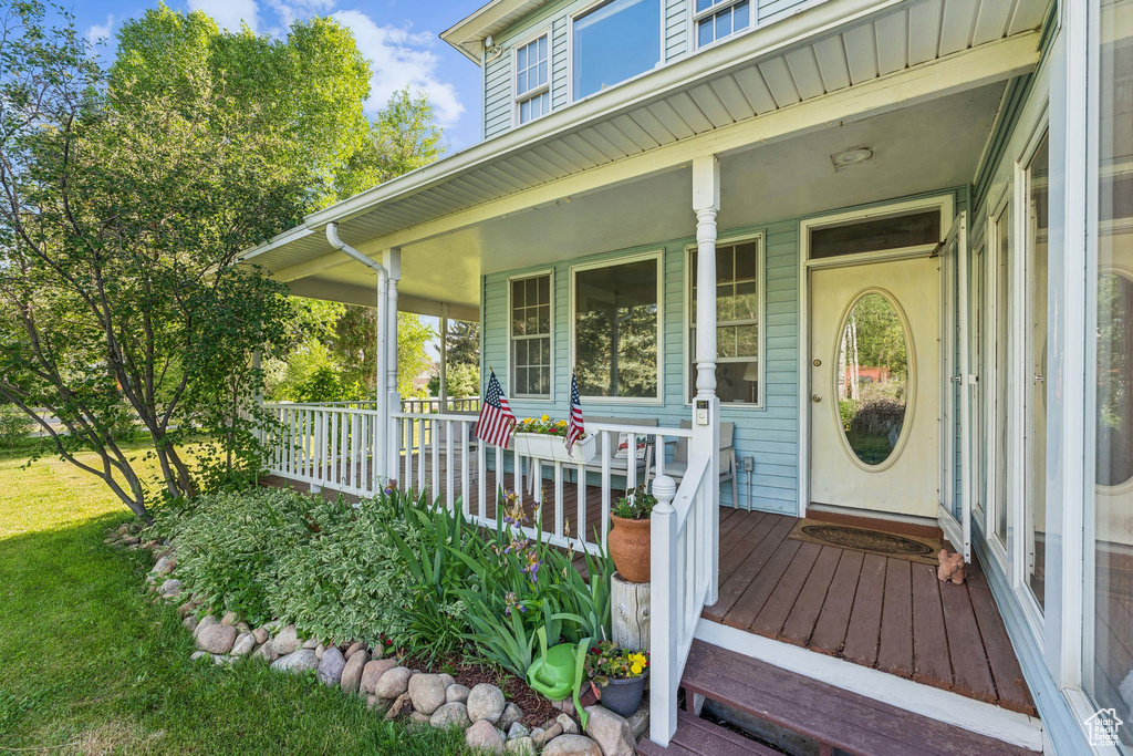 View of exterior entry featuring covered porch and a lawn