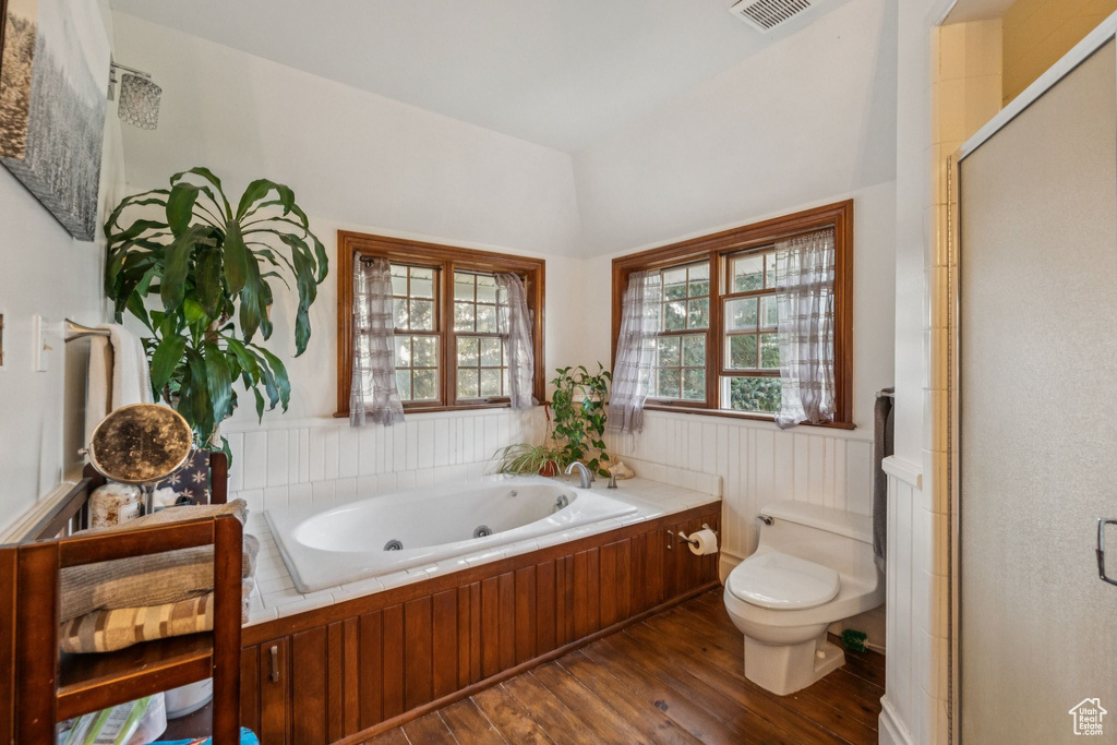 Full bathroom with wood finished floors, a tub with jets, a shower stall, and wainscoting