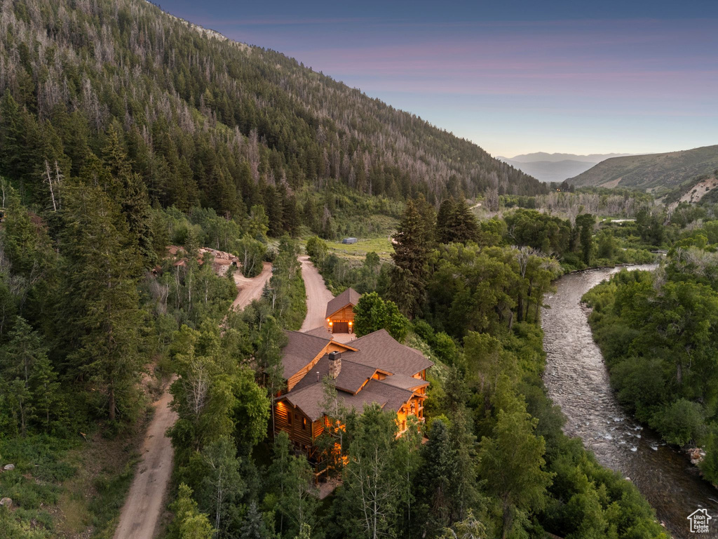 Aerial view of property and surrounding area featuring a heavily wooded area and a mountainous background