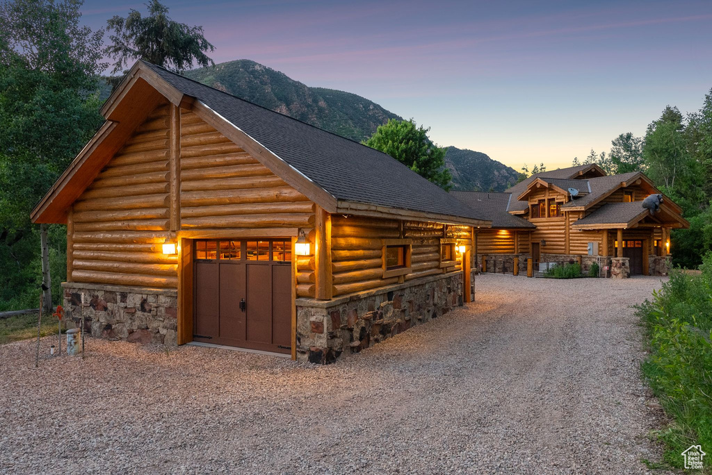 Log home with stone siding, log exterior, a mountain view, roof with shingles, and driveway