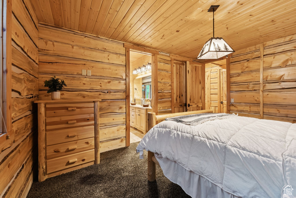 Bedroom with carpet floors, wooden ceiling, wood walls, and connected bathroom