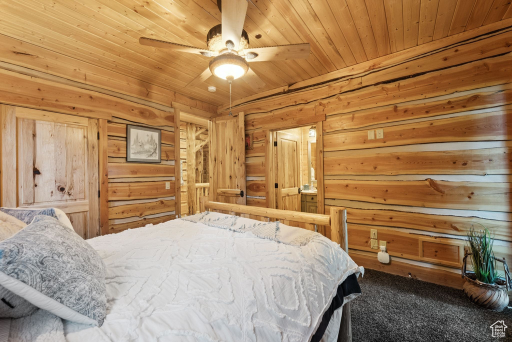 Carpeted bedroom with wood walls, wooden ceiling, and ceiling fan