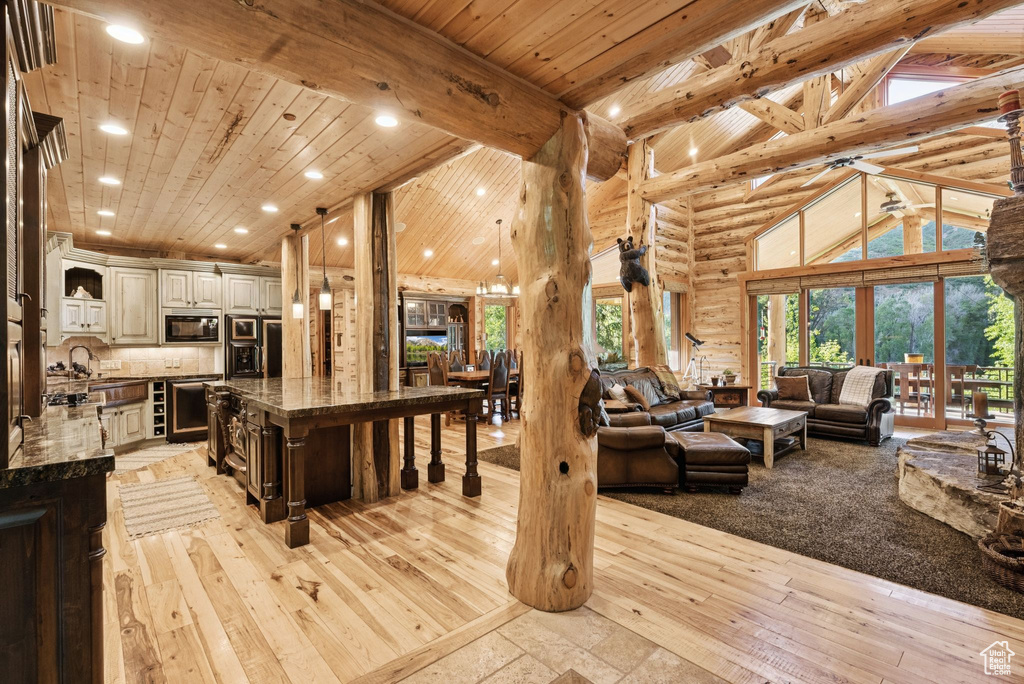 Living room with high vaulted ceiling, light wood finished floors, recessed lighting, a wooden ceiling with exposed beams, and beverage cooler