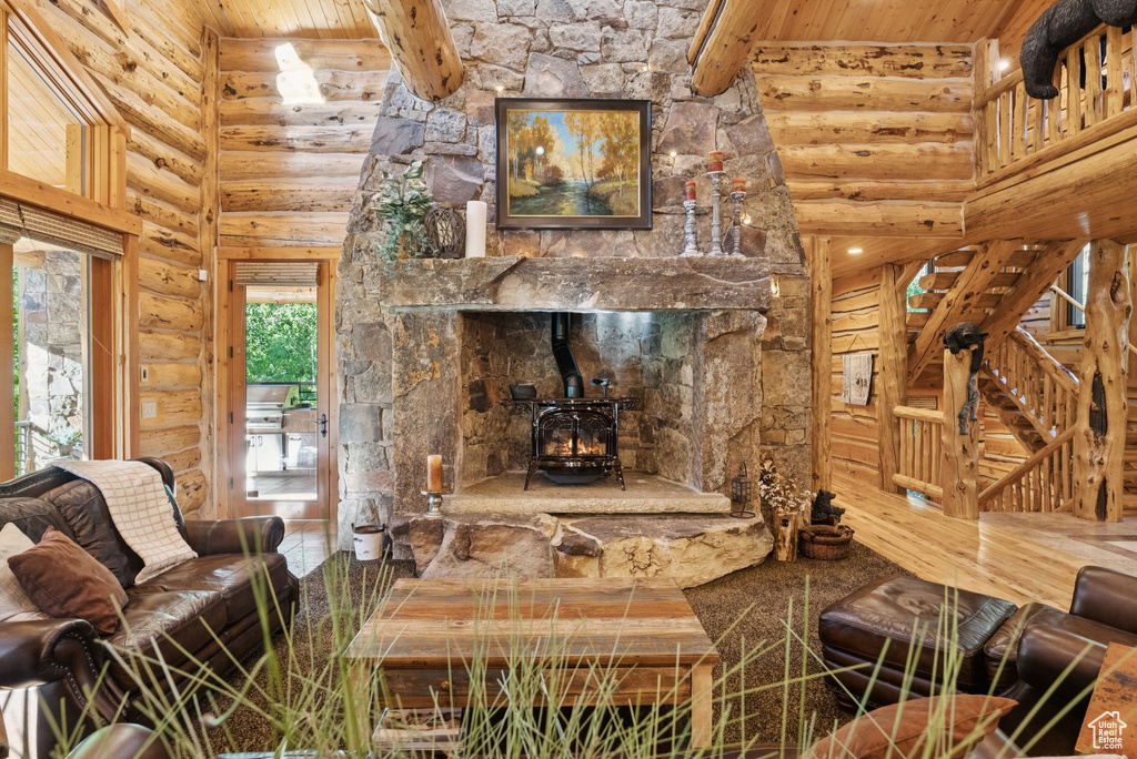 Living room with log walls, a wood stove, a wooden ceiling with exposed beams, and a high ceiling