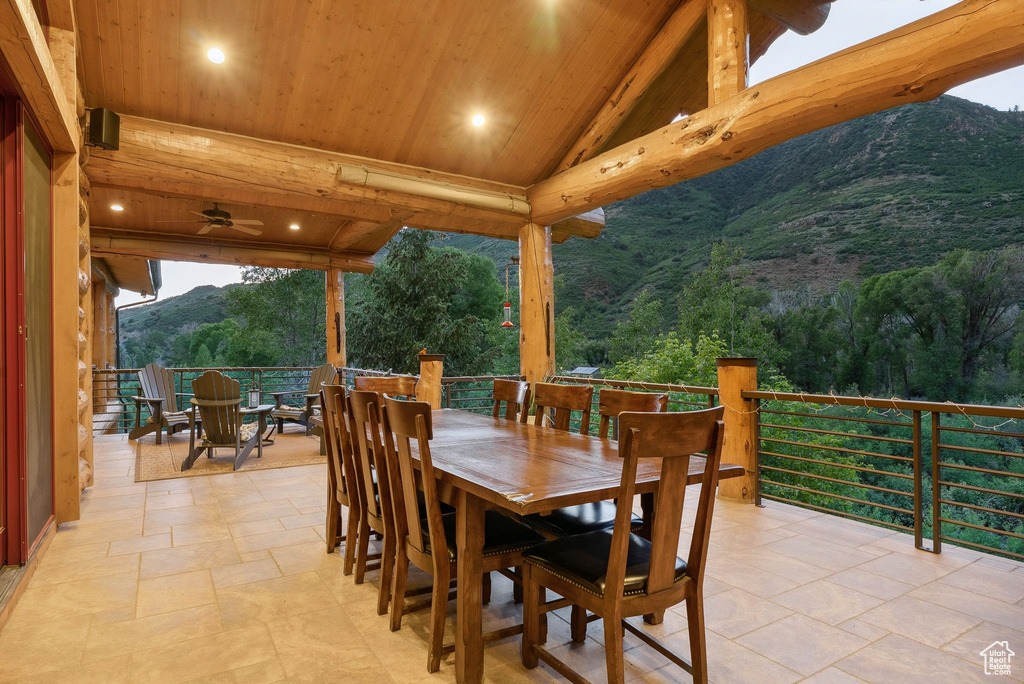 View of patio with outdoor dining space, a mountain view, ceiling fan, and a forest view