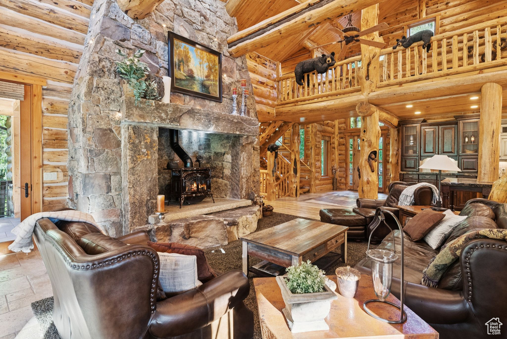 Living area with high vaulted ceiling, rustic walls, a wood stove, stone tile flooring, and wood ceiling