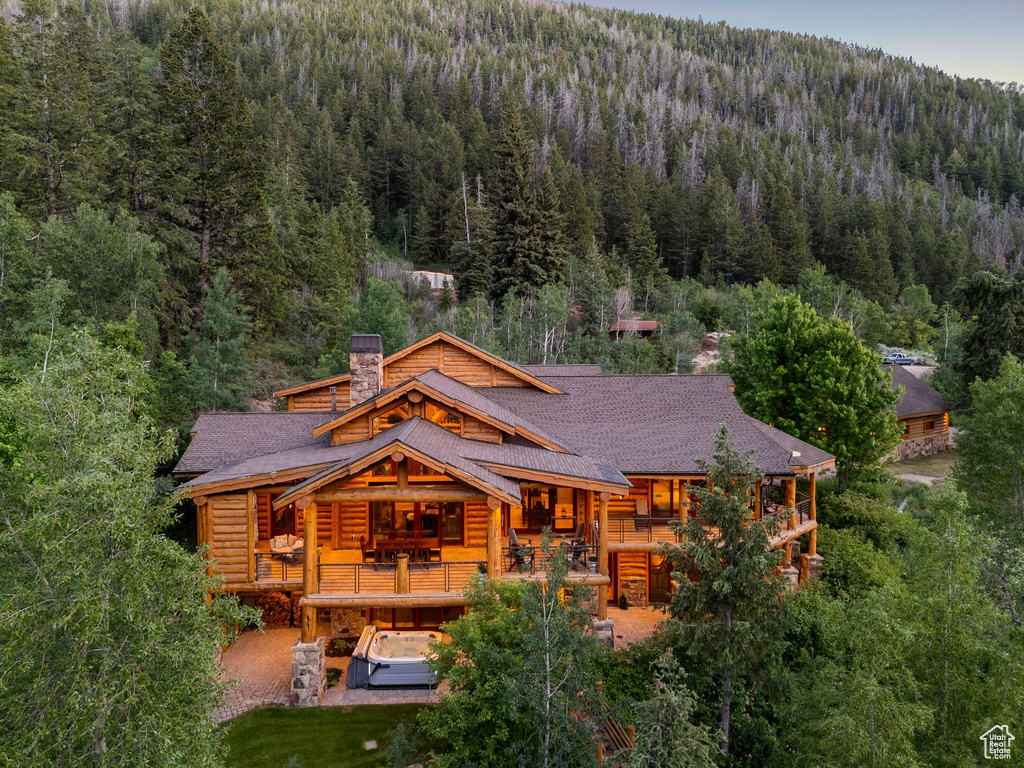 Back of property with a wooded view, log exterior, a chimney, and a shingled roof
