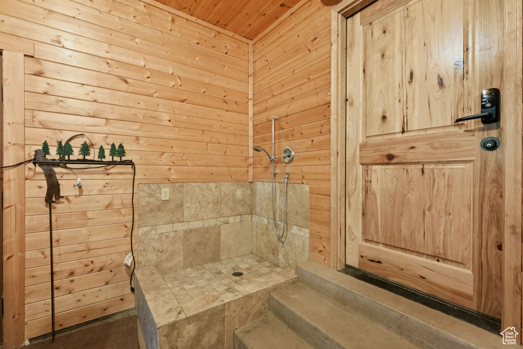 Bathroom with wood ceiling, tiled shower, and wooden walls