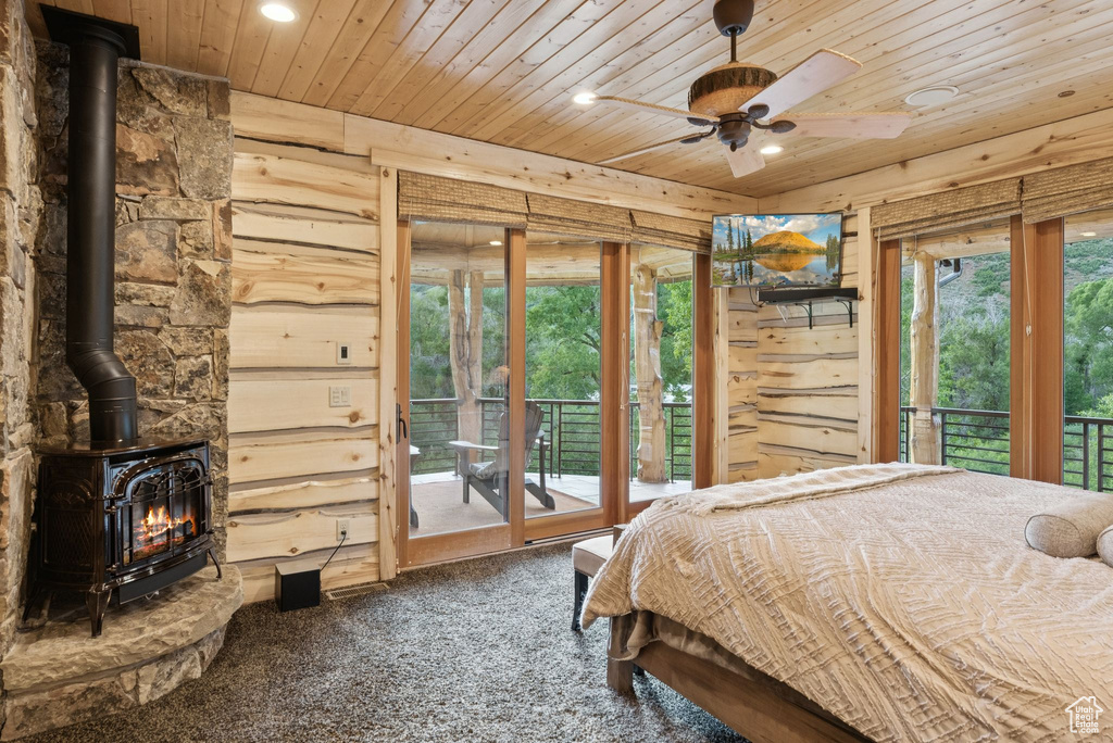 Carpeted bedroom featuring a wood stove, wooden ceiling, recessed lighting, and access to exterior