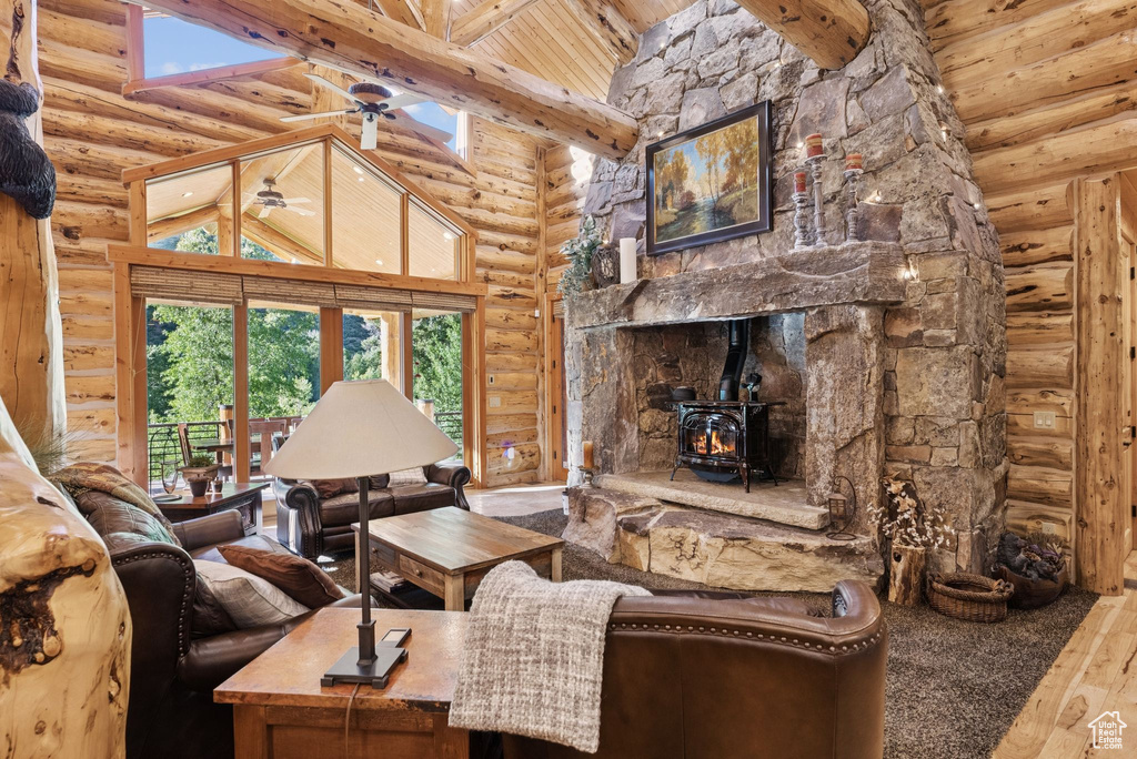 Living area with rustic walls, a wood stove, wood-type flooring, high vaulted ceiling, and ceiling fan