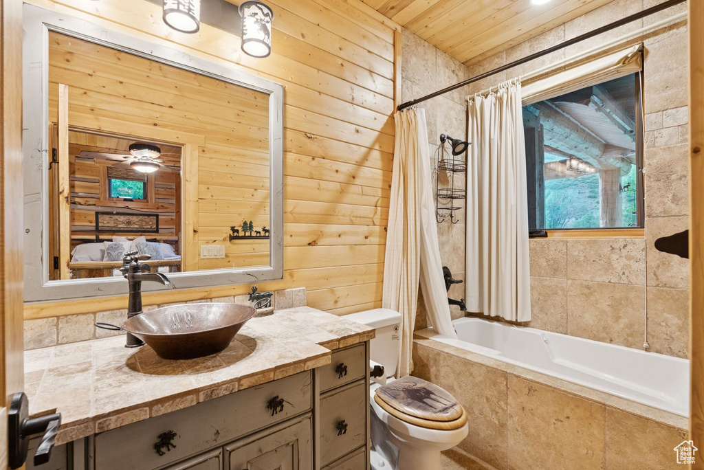 Full bathroom featuring wood walls, vanity, tiled shower / bath combo, and wood ceiling