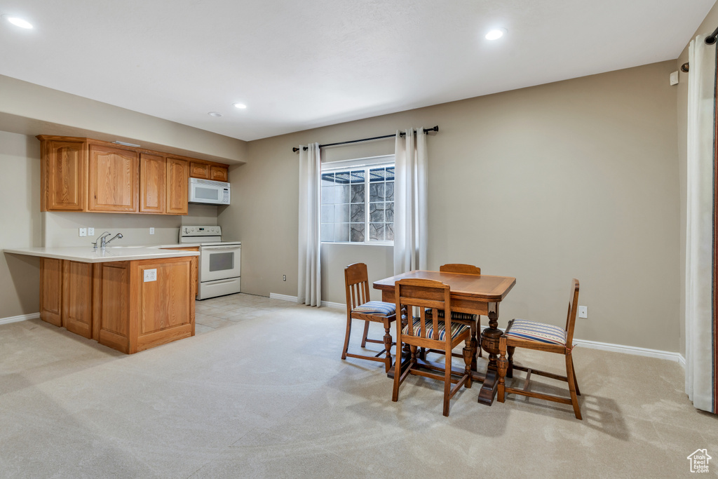 Kitchen featuring white appliances, light colored carpet, a peninsula, recessed lighting, and light countertops