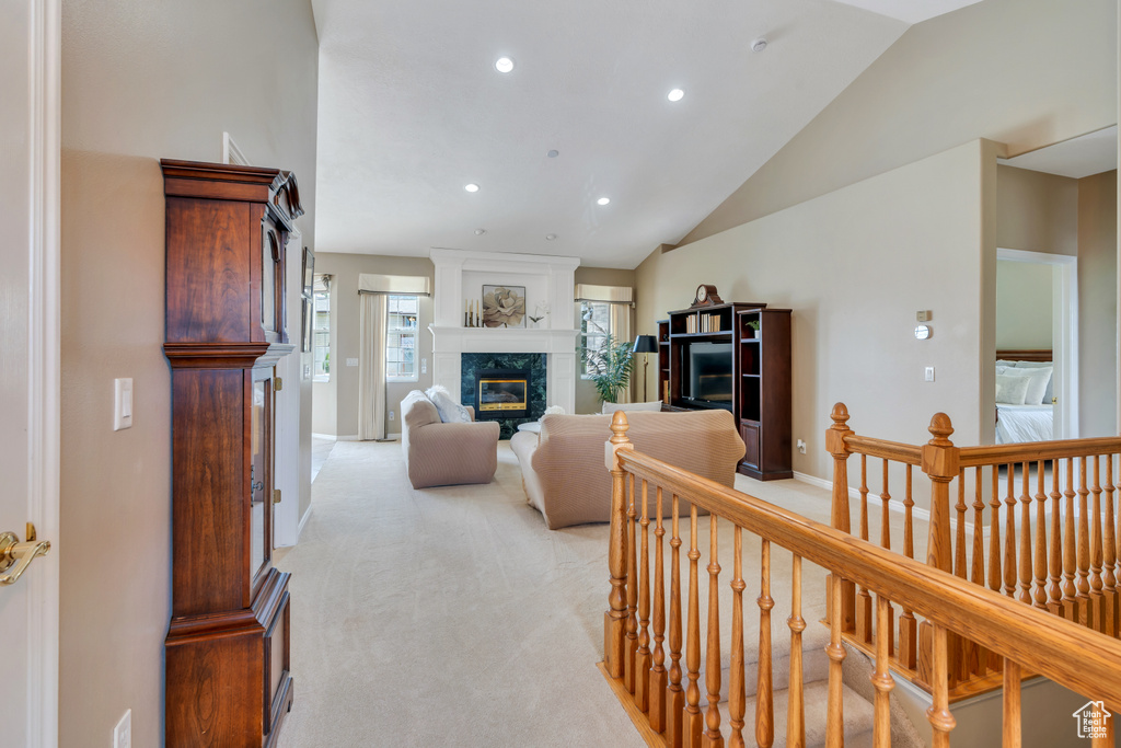 Living room with vaulted ceiling, a premium fireplace, recessed lighting, and light carpet