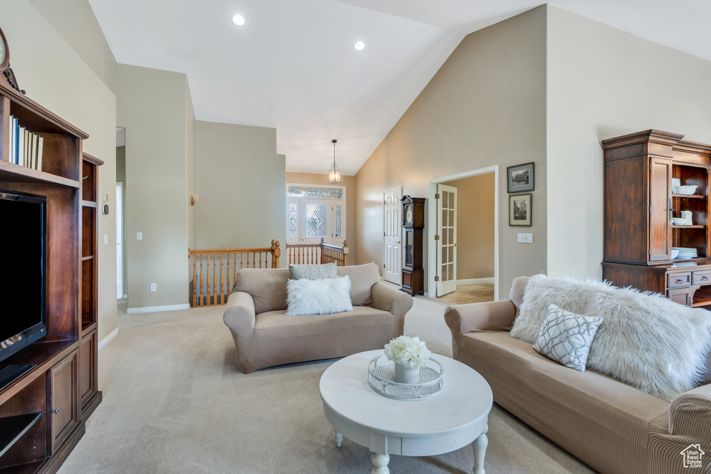 Living area featuring high vaulted ceiling, light carpet, and recessed lighting