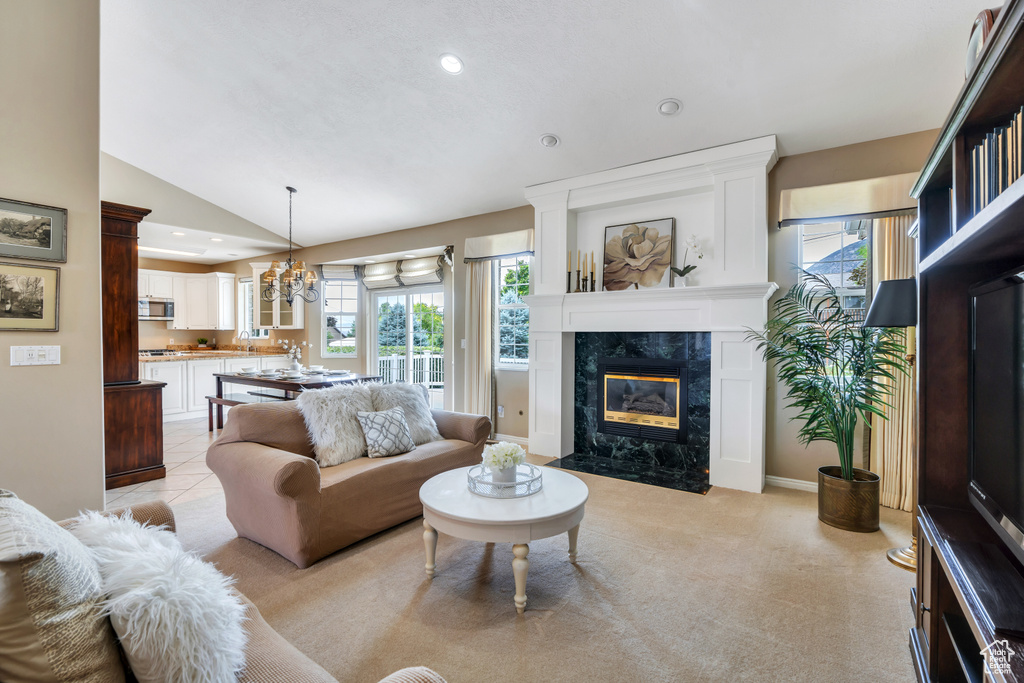 Living area featuring a fireplace, vaulted ceiling, healthy amount of natural light, recessed lighting, and a chandelier