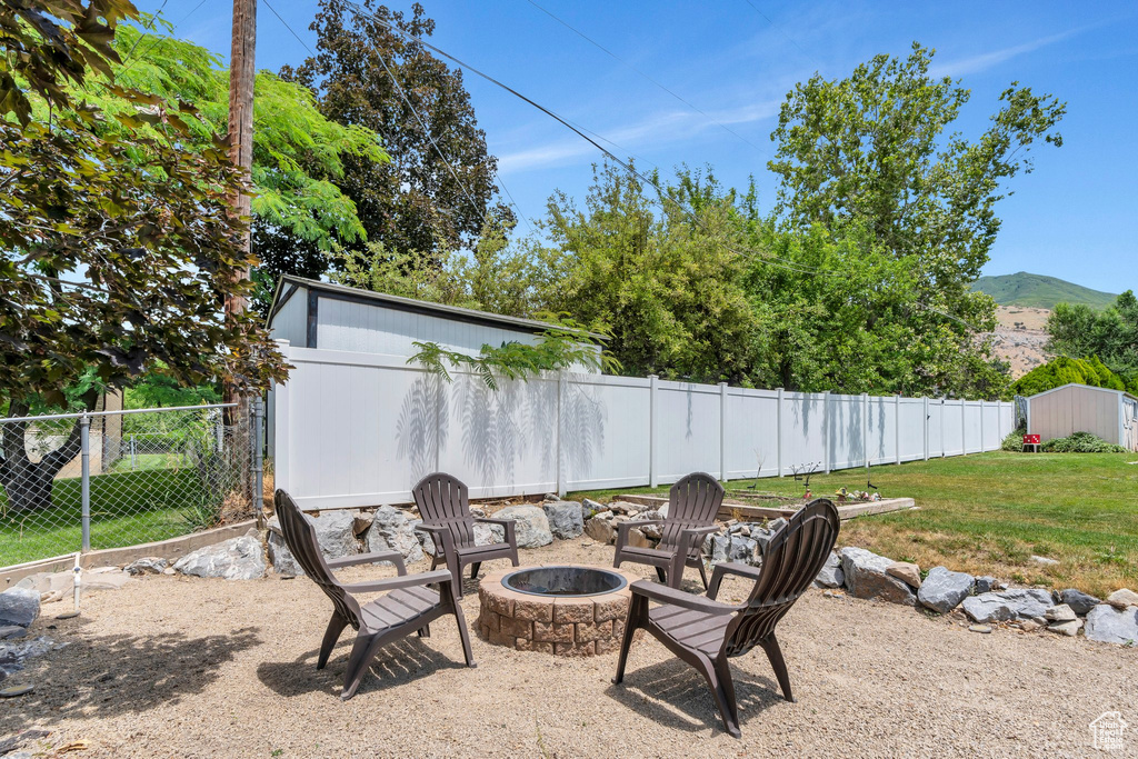 Fenced backyard with an outdoor fire pit, a storage unit, and a mountain view