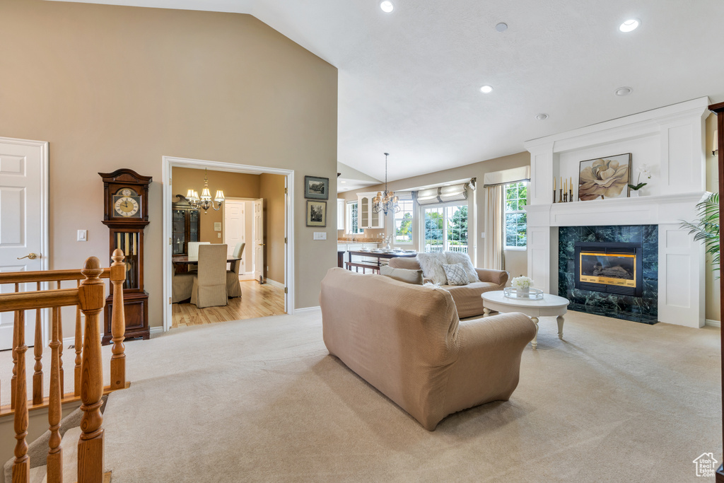 Living area featuring light carpet, a chandelier, a high end fireplace, recessed lighting, and high vaulted ceiling