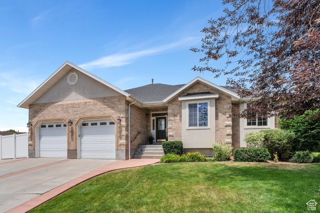 Single story home with concrete driveway, an attached garage, stucco siding, and stone siding
