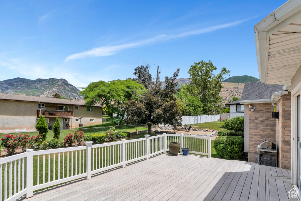 Wooden terrace featuring a mountain view, a yard, and area for grilling