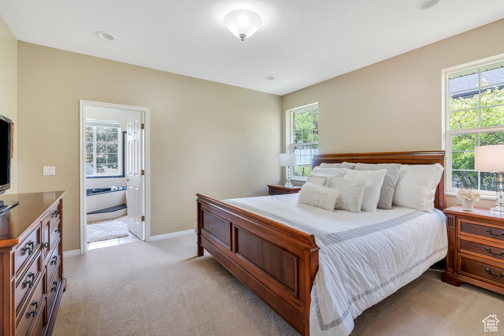 Bedroom featuring light colored carpet and ensuite bathroom