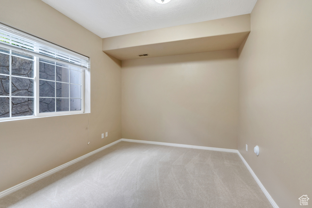 Spare room featuring carpet flooring and baseboards
