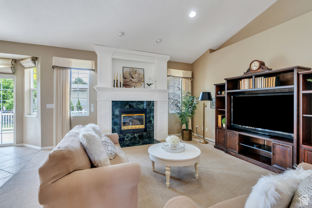 Living room with a premium fireplace, plenty of natural light, lofted ceiling, recessed lighting, and tile patterned floors