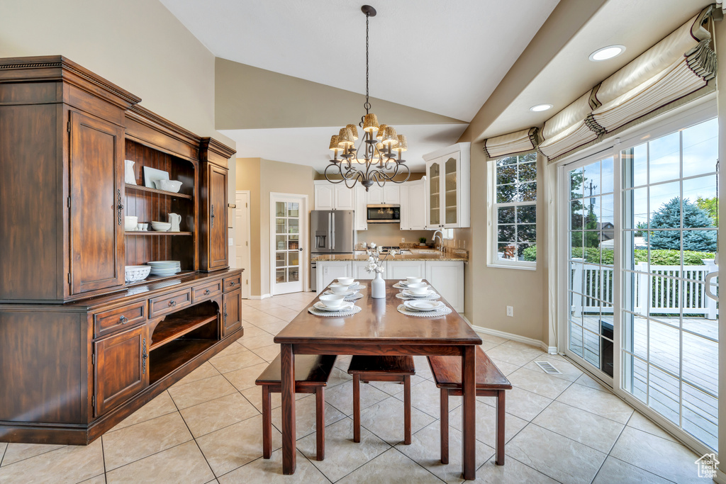 Dining area featuring vaulted ceiling, a chandelier, light tile patterned flooring, and recessed lighting