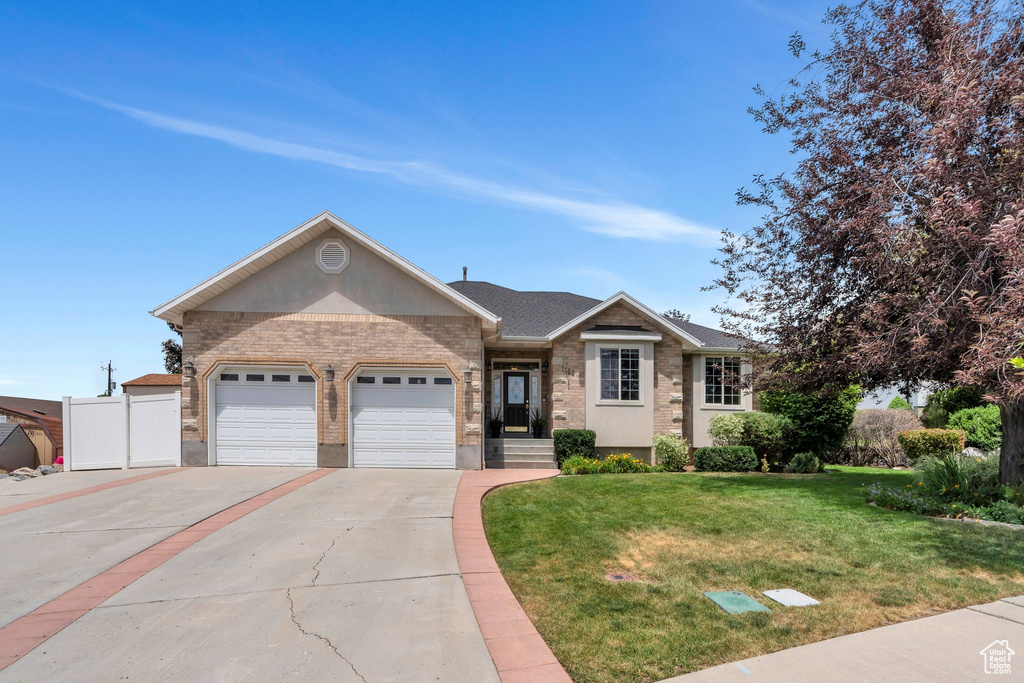 Single story home with driveway, an attached garage, brick siding, a front lawn, and a shingled roof