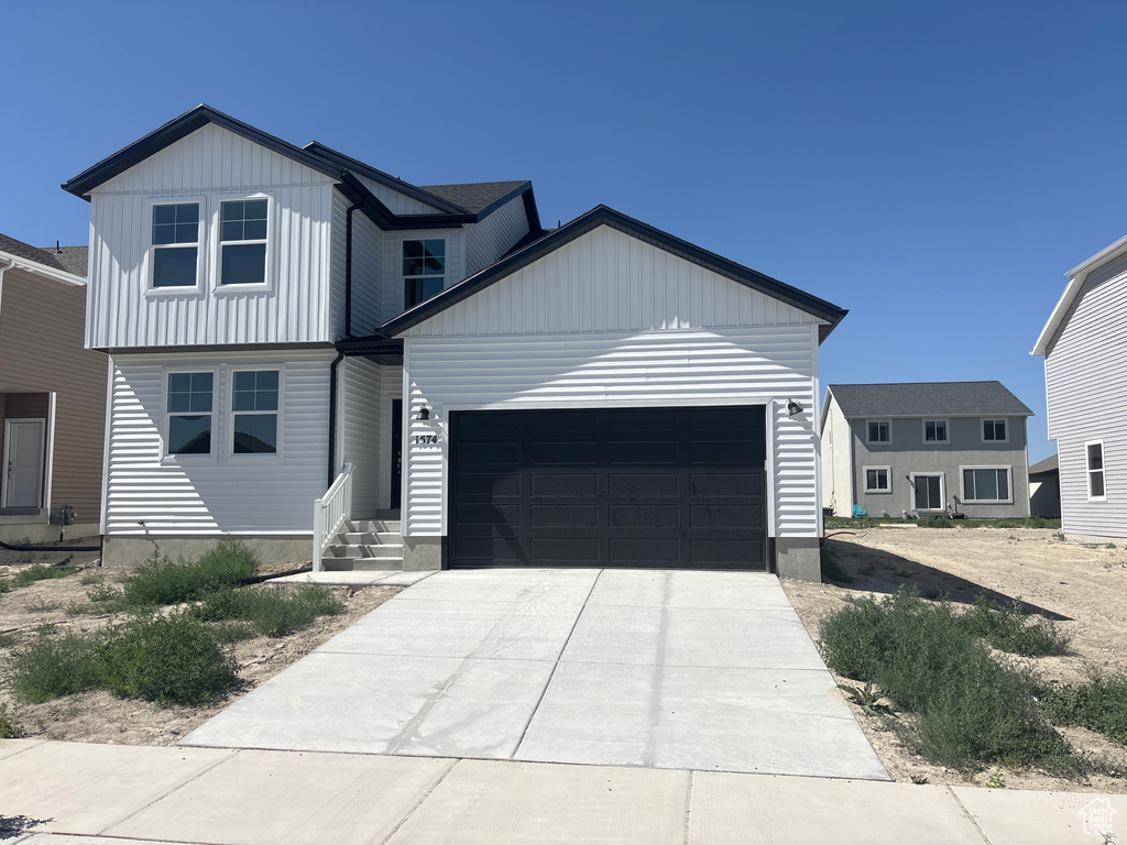 View of front of home featuring an attached garage, driveway, and board and batten siding