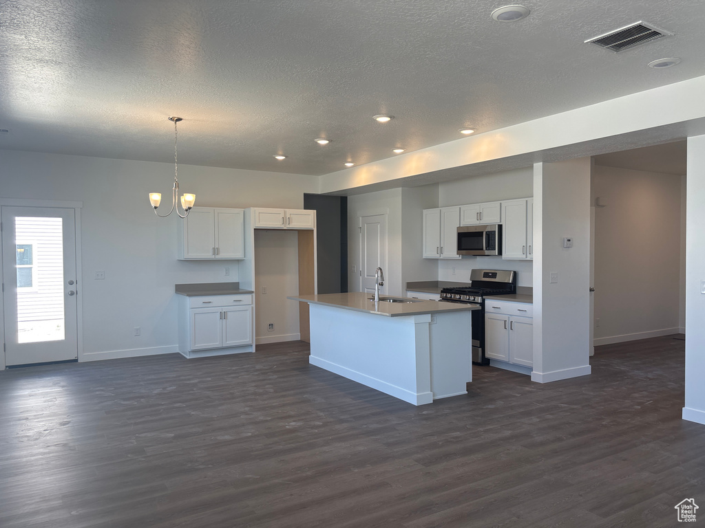 Kitchen featuring stainless steel appliances, a textured ceiling, dark wood finished floors, white cabinetry, and recessed lighting
