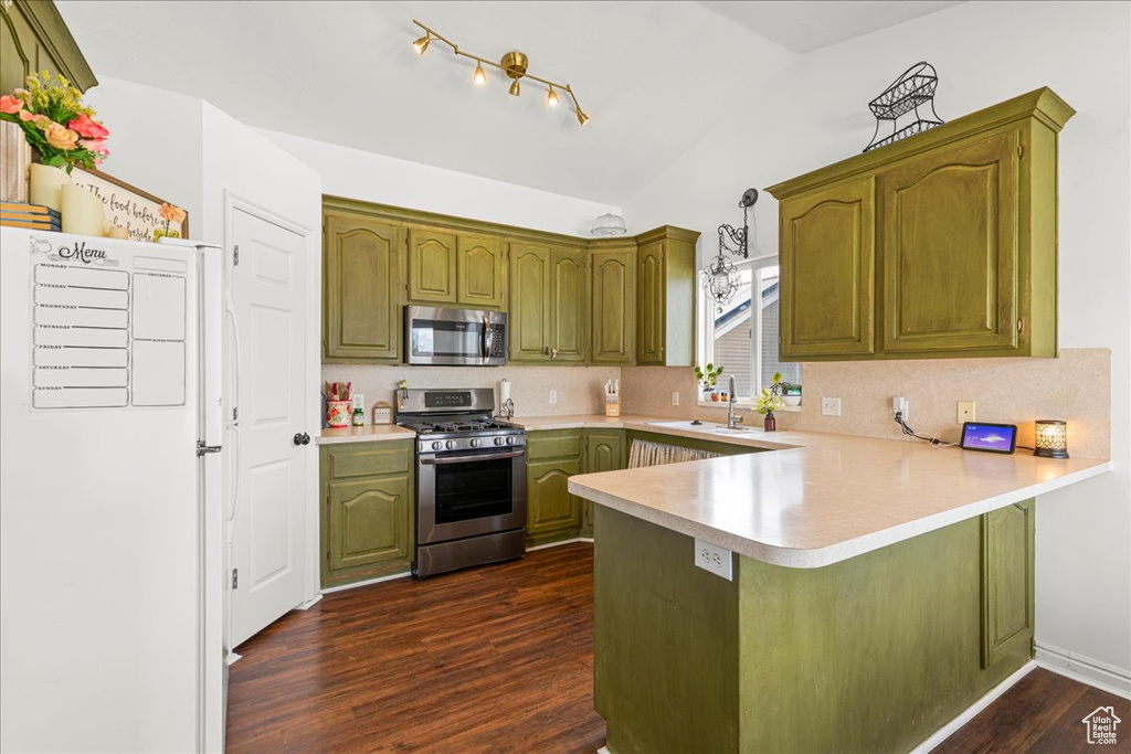 Kitchen with stainless steel appliances, a peninsula, green cabinetry, light countertops, and dark wood-style floors