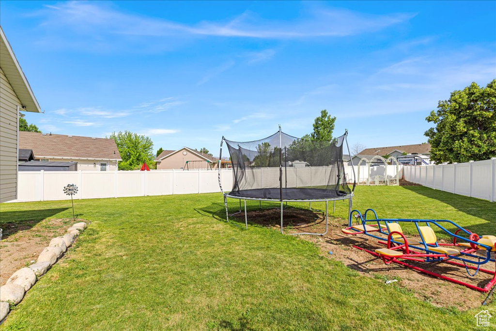 Fenced backyard featuring a trampoline and a residential view