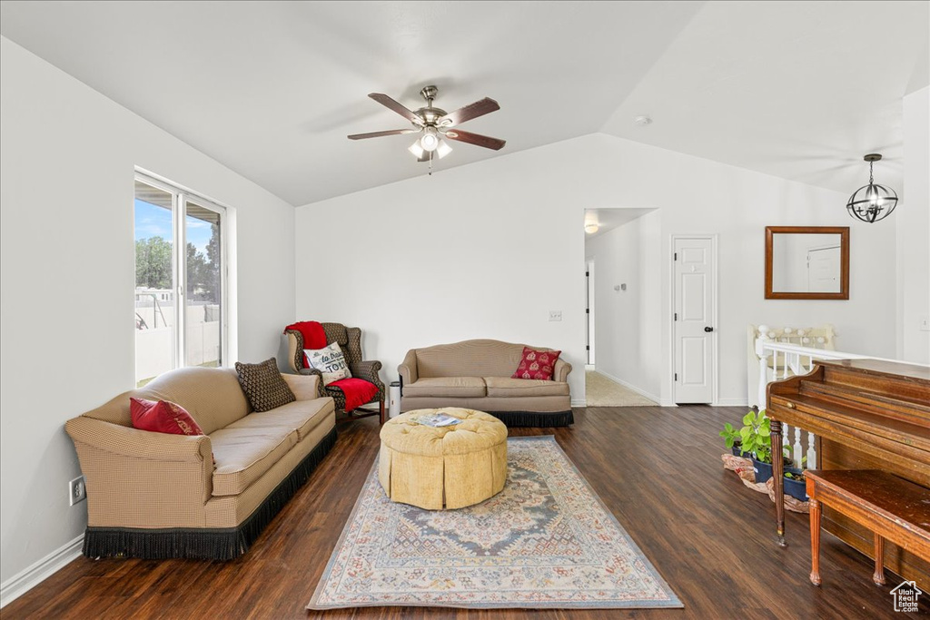 Living room with lofted ceiling, ceiling fan, and dark wood-type flooring