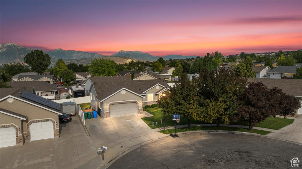 View of front facade featuring an attached garage, driveway, a residential view, a mountain view, and stucco siding